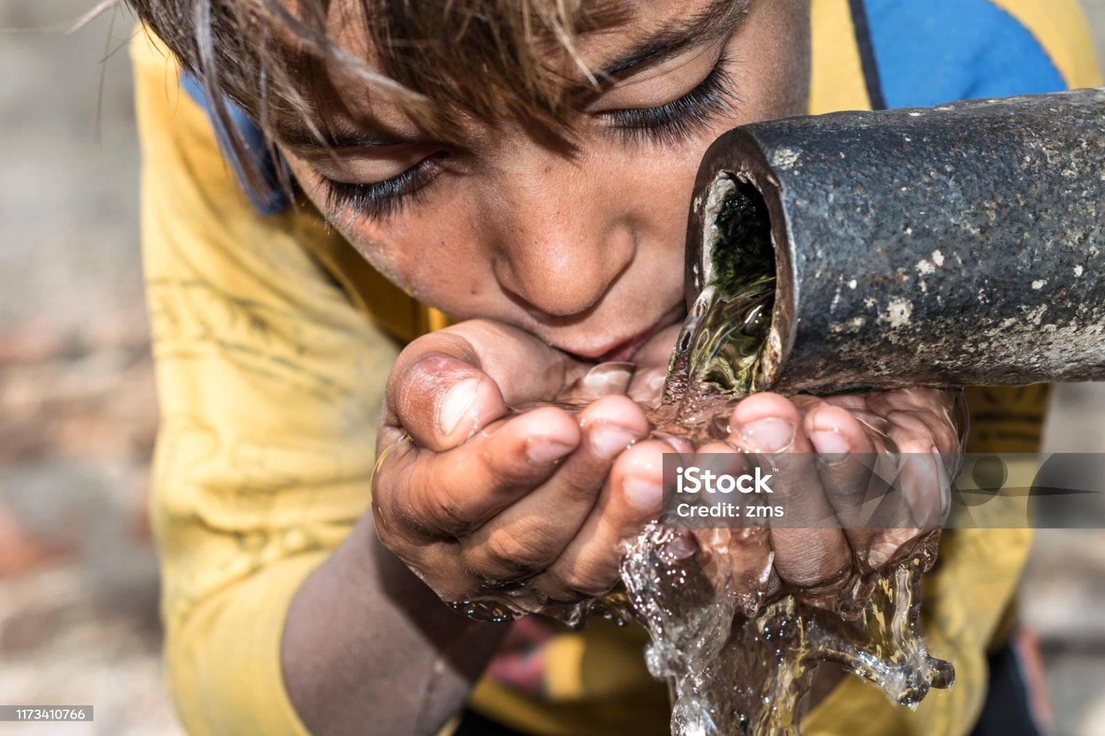 a young thirsty boy is drinking clean and sweet water